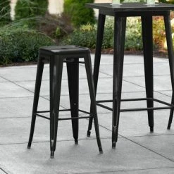 LT&S Alloy Series Lancaster Table & Seating Alloy Series Distressed Black Stackable Metal Indoor / Outdoor Industrial Barstool With Drain Hole Seat