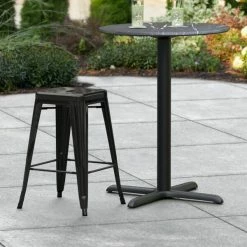 LT&S Alloy Series Lancaster Table & Seating Alloy Series Black Stackable Metal Indoor / Outdoor Industrial Cafe Counter Height Stool With Drain Hole Seat